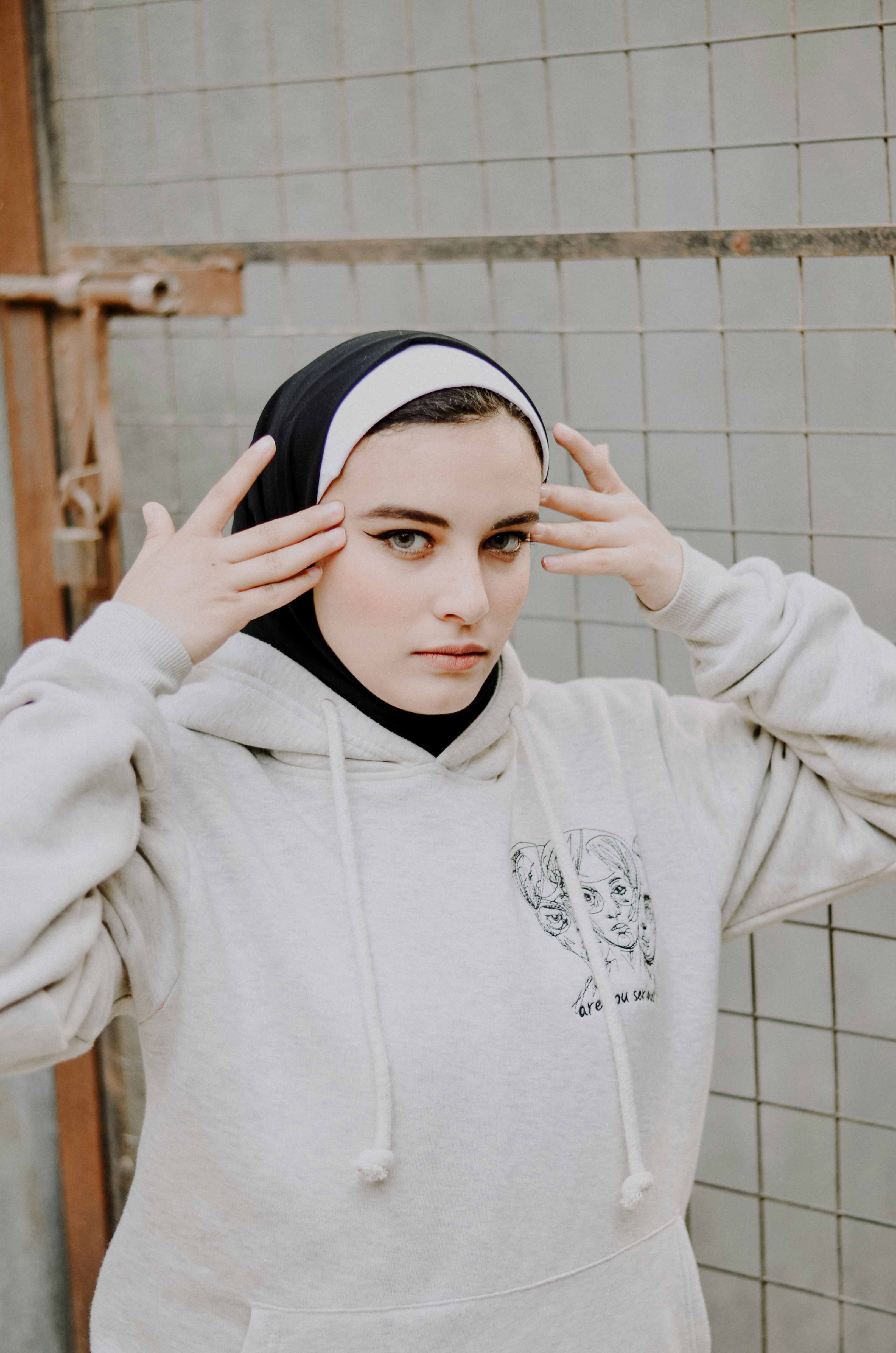 woman in white hoodie covering her face with her hands